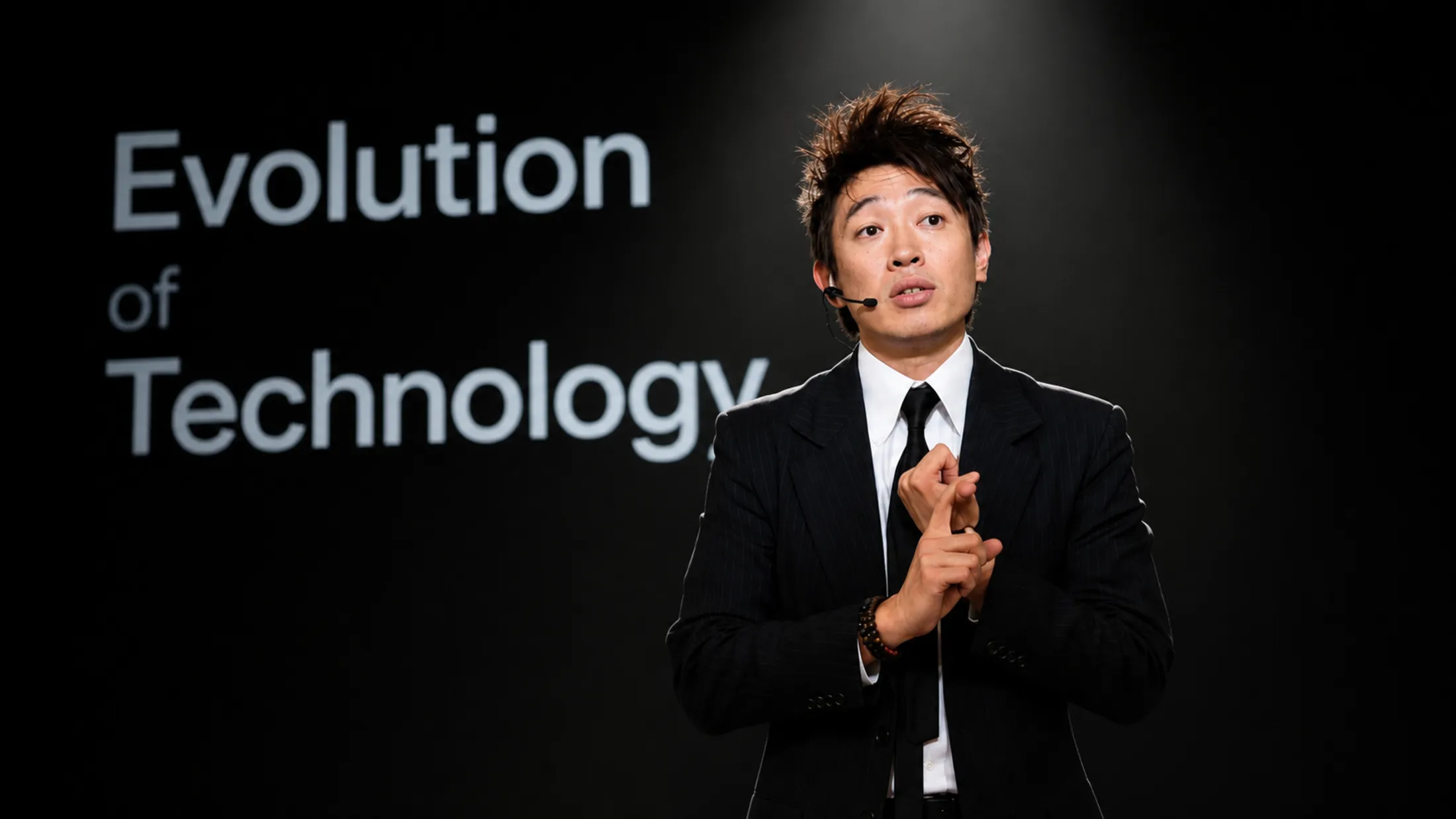 AJ presenting on stage in front of an 'Evolution of Technology' slide